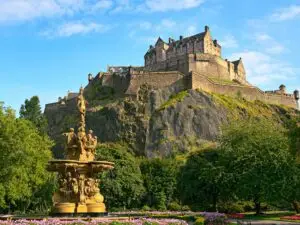 external view of edinburgh castle with fountain in focus in foreground