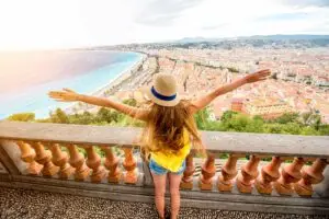 Young woman enjoying panoramic view of Nice, France, from a high viewpoint with arms wide open.