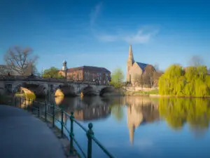 English Bridge over River Severn with reflection, historic church, and willow tree in Shrewsbury, England, UK.