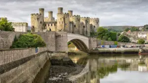 Conwy Castle, a medieval fortification in Wales, reflected in water with surrounding town and landscape