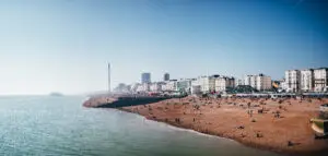 Panoramic view of Brighton Beach with crowded pier and coastline, highlighting the vibrant tourist spot in Brighton, United Kingdom