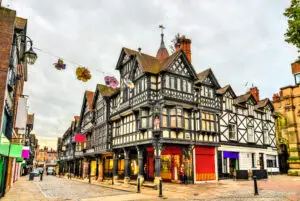 Traditional Tudor-style buildings on a cobblestone street in Chester, England, showcasing historic English architecture.